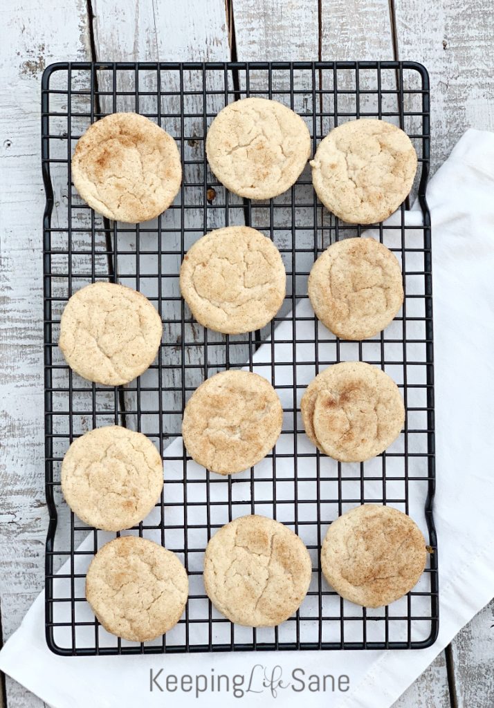 overhead view of eggless snickerdoodle cookies on black wire cooling rack on old wooden table