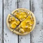 overhead and closeup view of round mini breakfast pizza with a slice coming out