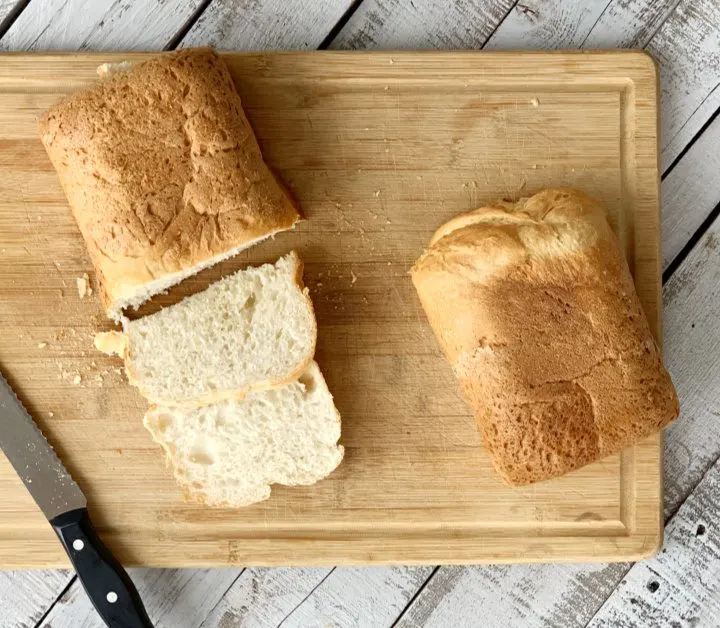 Overhead view of bread on a cutting with bread knife with a few slices cut.