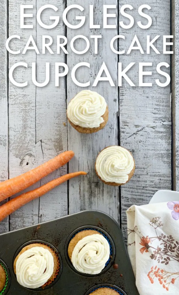 overhead view of egg free carrot cake muffin with buttercream frosting with a couple of carrots laying on a wooden table