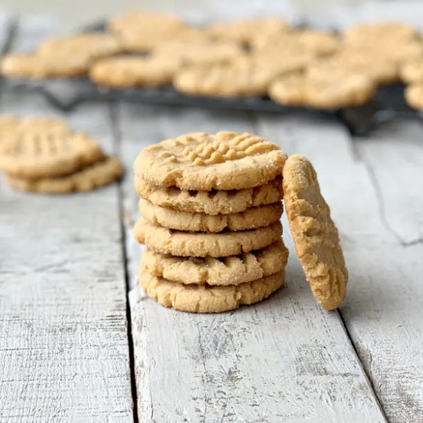 Stack of eggless peanut butter cookies with another cookie laying against stack