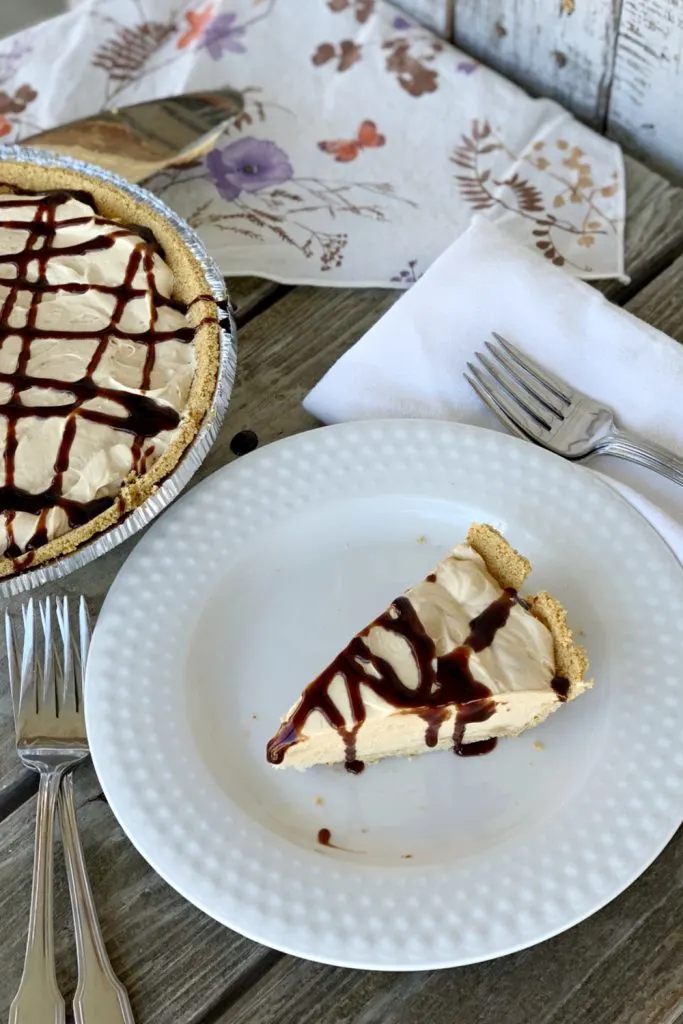 peanut butter icebox pie with chocolate sauce on white place on wooden table
