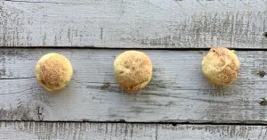 3 mini applesauce muffins lined up on a wooden table