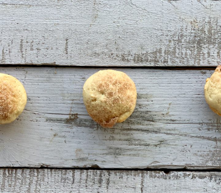 3 mini applesauce muffins lined up on a wooden table