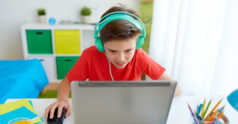 boy at desk with headphones working on computer