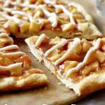 apple pie pizza on pizza baking stone with slice coming out