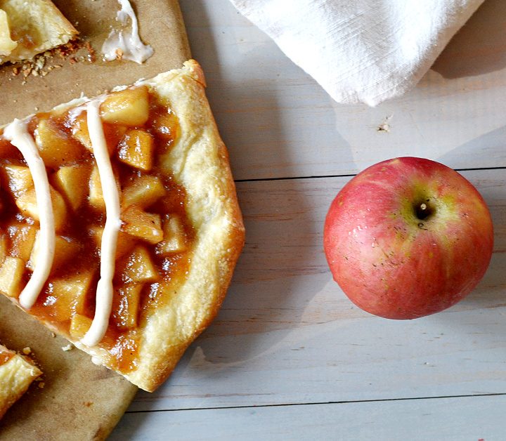 Slice of apple pie pizza with 2 red apples