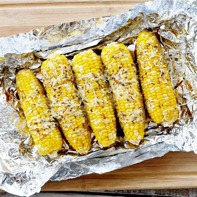 corn on the cob in foil with cheese on top on top of foil
