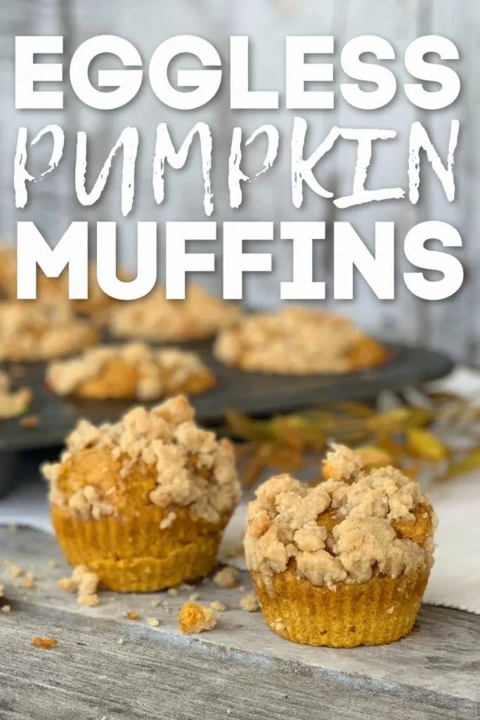 2 eggless pumpkin muffins with crumbles on top with muffin tin in background