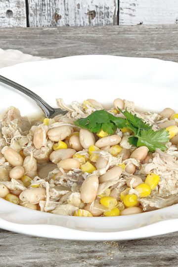 White Bowl of white chicken chili with napkin and cilantro