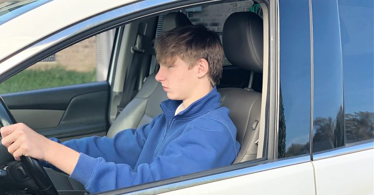 up close boy teen in blue sweatshirt driving white van