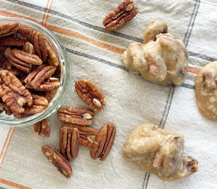 small bowl of pecans and pecan pralines on fall tablecloth