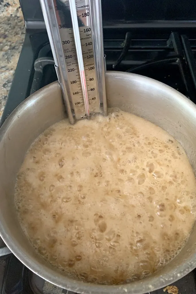 sugar boiling in a pot on the stove with a thermometer