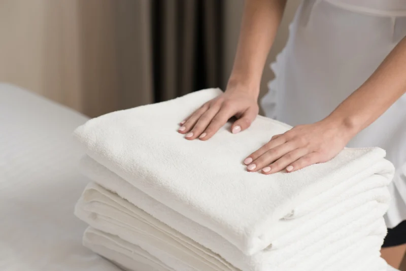 stack of white towels with lady places her hands on top