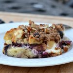 white bowl on cutting board with french toast casserole with blueberries