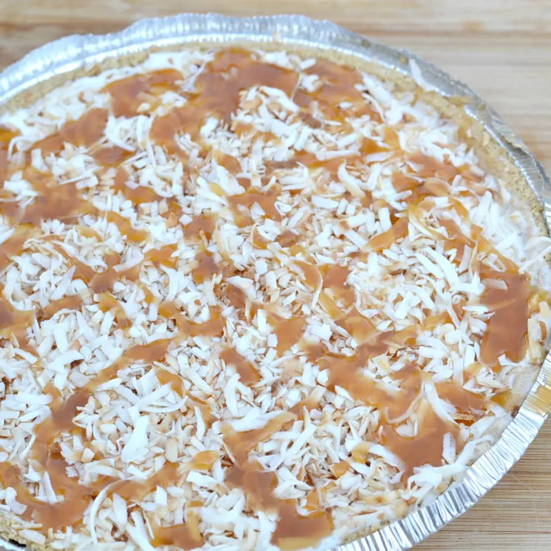 top of coconut ice cream pie with toasted coconut and caramel drizzled on top