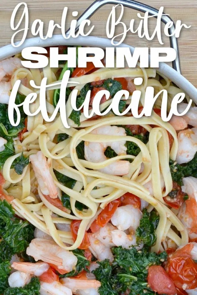 overhead view of fettuccine, shrimp, cooked kale and red halved cherry tomatoes