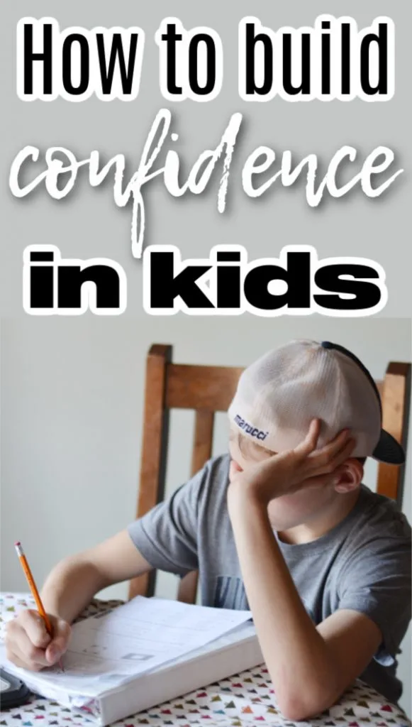 boy sitting at kitchen table doing homeowrk with hand on head and hat backwards