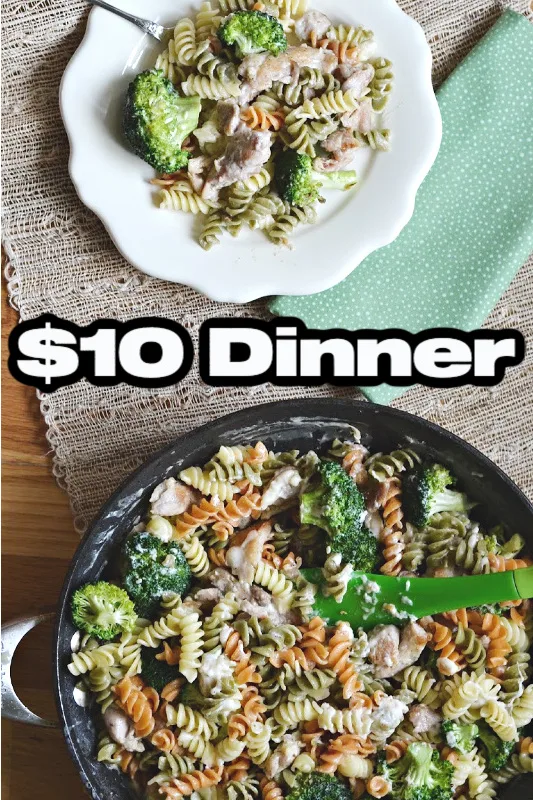 overhead view of skillet with pasta, broccoli and chicken meal with small white plate with and green napkin