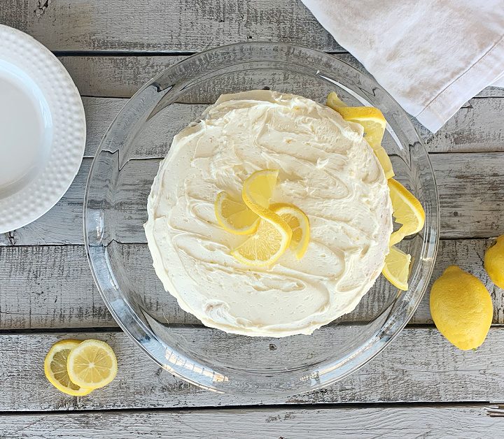 overhead view of lemon cake on clear cake stand with lemon garnish