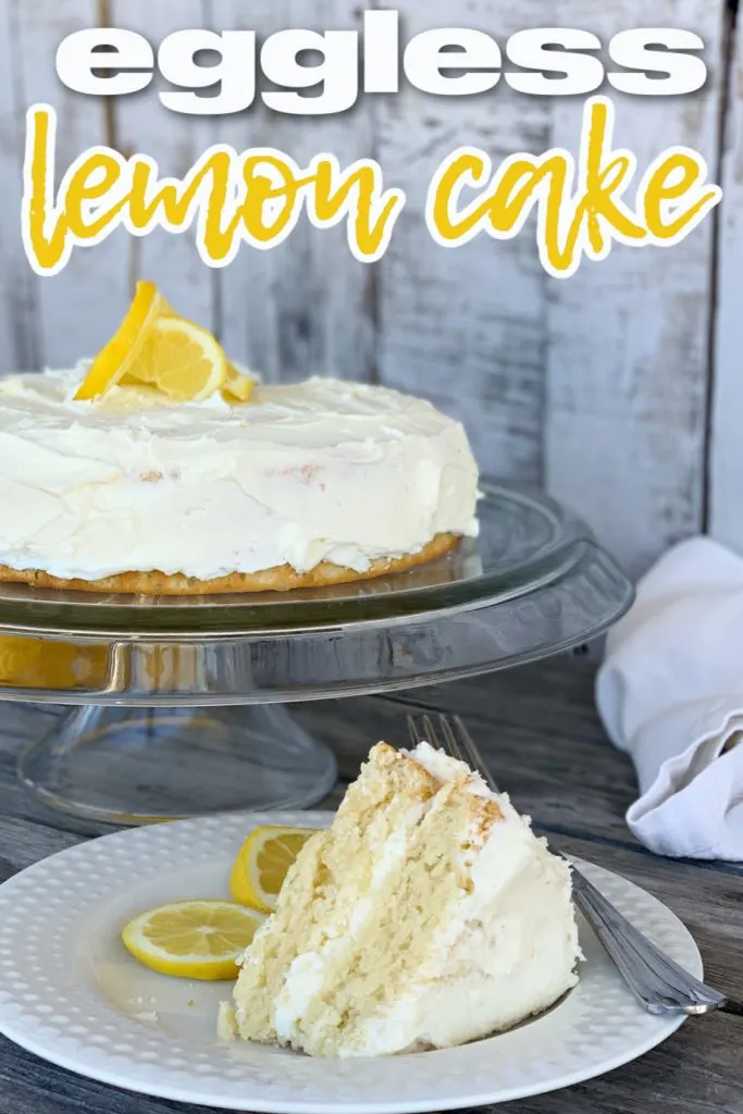 lemon cake with lemon garnish on clear cake stand with whiteplate with a slice of cake