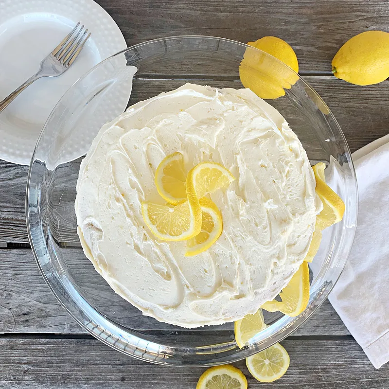 overhead view of lemon cake on clear cake stand with lemon garnish