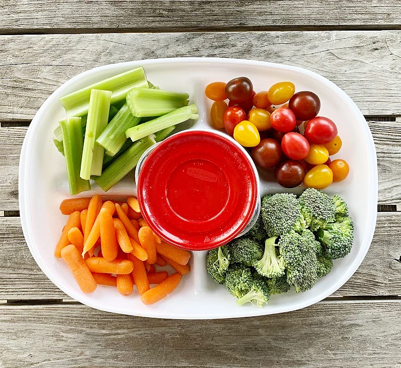 overhead view of veggie tray with celery, colorful tomatoes baby carrots and chopped broccoli