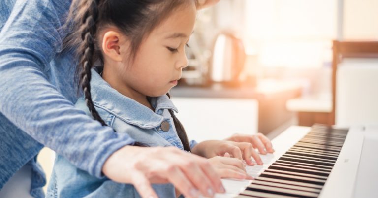 Asian young pianist teacher teaching girl kid student to play piano