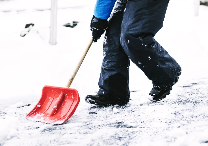 Child shovelling snow and cleaning the driveway.