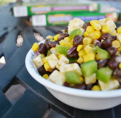 closeup of Mexican corn black bean salad in a white bowl on an outside iron table