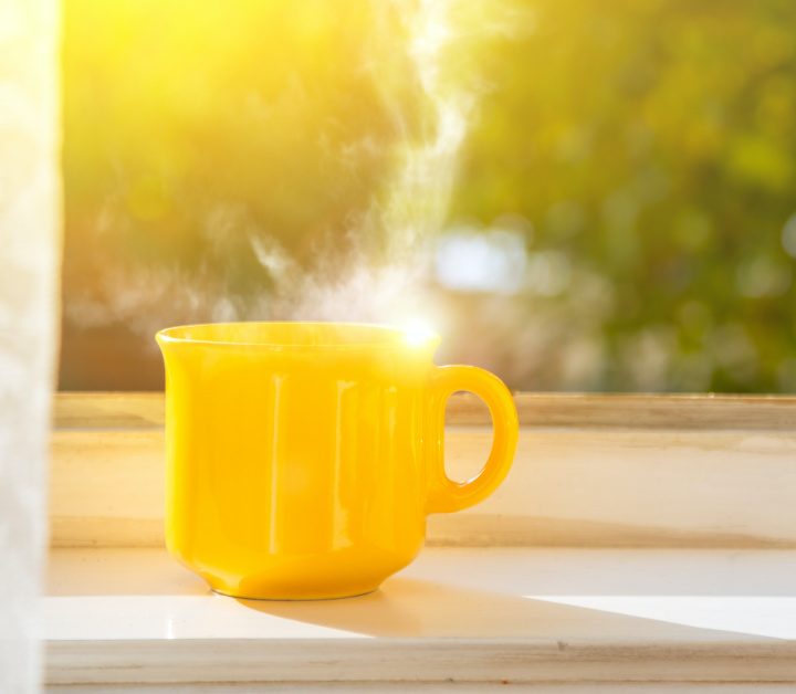 Cup on the window with sun and defocused nature background