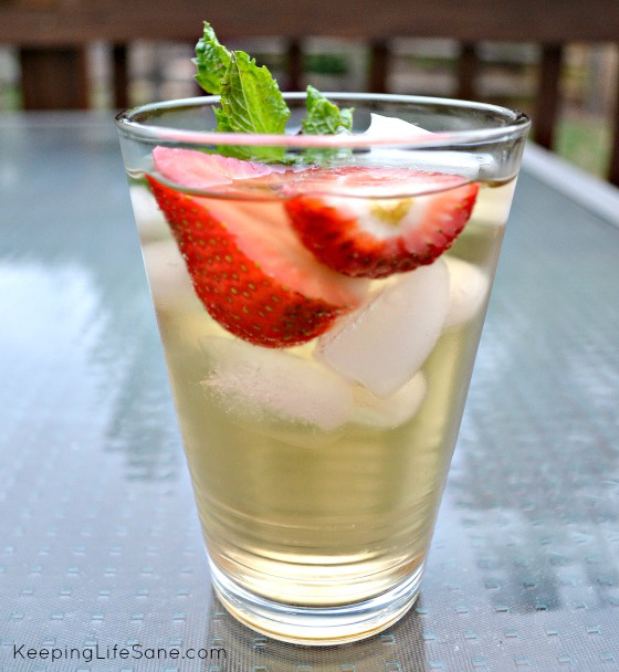 glass of green tea with ice cubes, strawberries and mint leaves