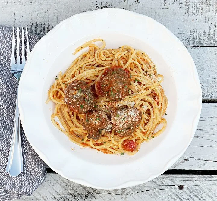 overhead shot of white bowl with with spaghetti and meatballs