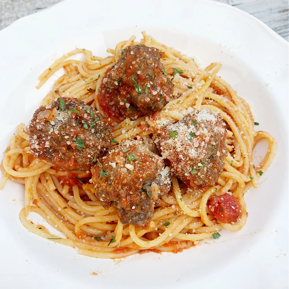 closeup of white bowl with with spaghetti and meatballs