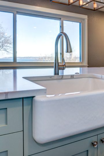 Clean kitchen counter with light blue cabinets with white sink