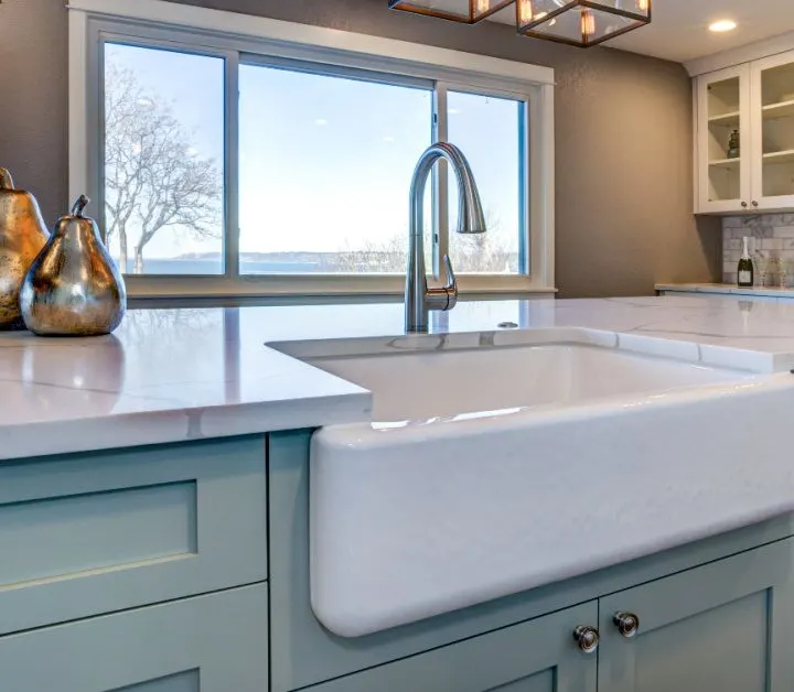 Clean kitchen counter with light blue cabinets with white sink