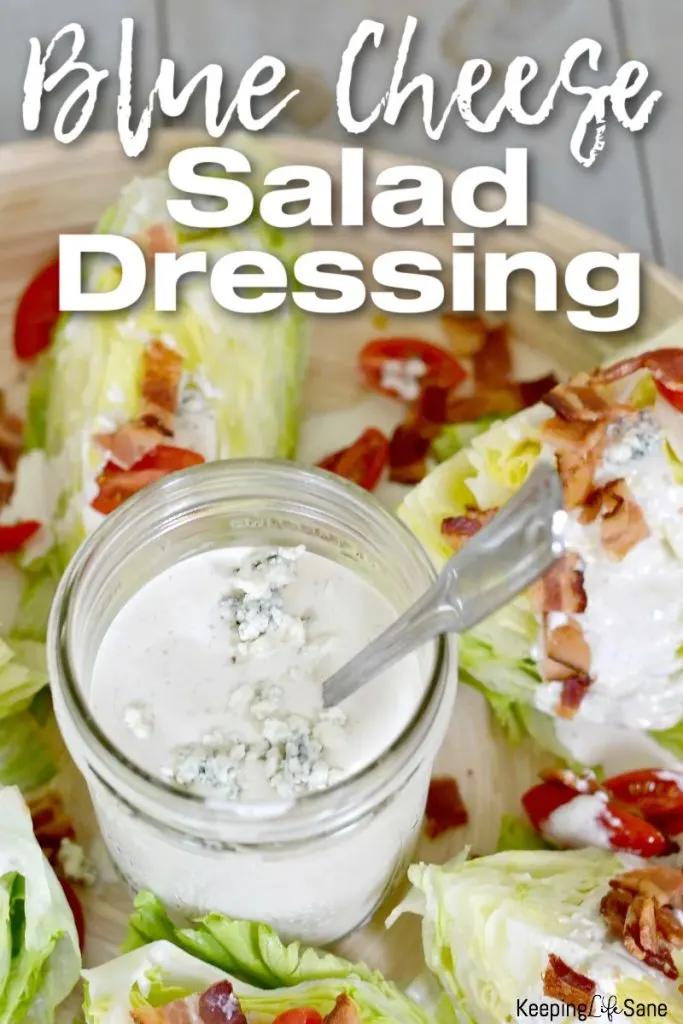blue cheese salad dressing in jar on wood platter with wedge salad with bacon and cherry tomatoes