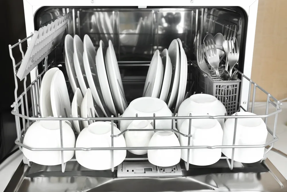 Open dishwasher with clean utensils in it