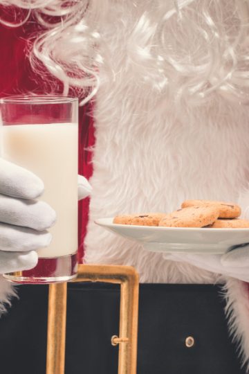 Santa Claus holding plate of cookies and glass of milk