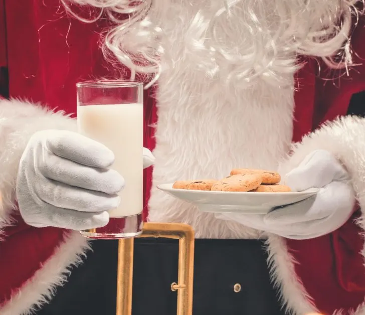 Santa Claus holding plate of cookies and glass of milk