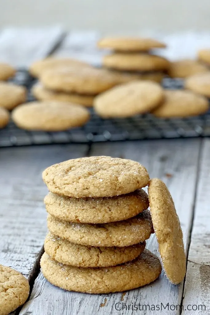 stack of eggless ginger cookies on wooden table with wire rack in the background