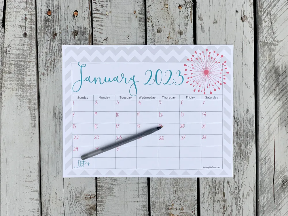 January 2023 Calendar laying on wooden table with pen