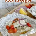 Mediterranean Cod Recipe in foil with red onions,and tomatoes on lare cutting board