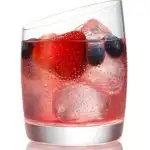 light red cocktail in clear glass with ice cubes, strawberries and blueberries