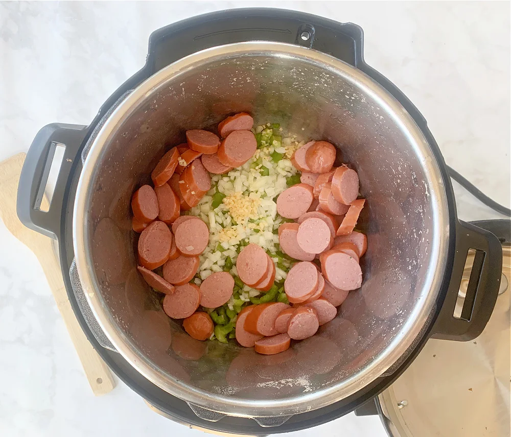 Overhead view of 15 bean soup ingredients (sausage, onions, garlic, celery and green peppers) in an Instant Pot