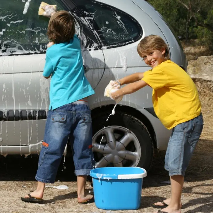 Boy in blue shirt washing a car