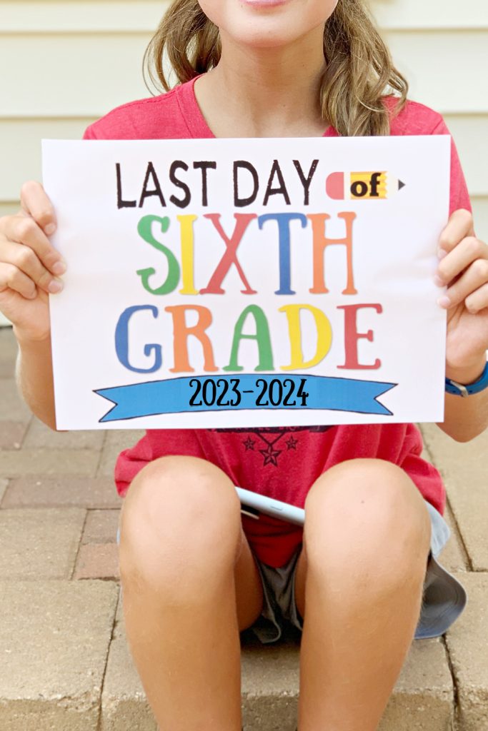 girl sitting on brick steps holding last day of school printable sign