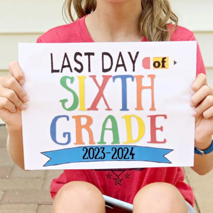 girl sitting on brick steps holding last day of school printable sign