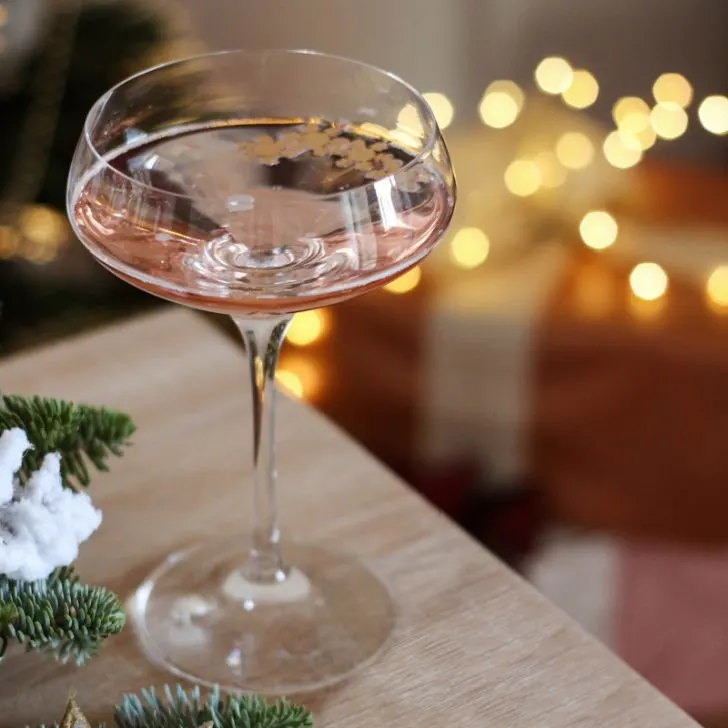 champagne glass with Christmas lights in the background and Christmas ornament in the foreground