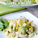 shrimp avocado salad with corn on white plate with cilantro garnish